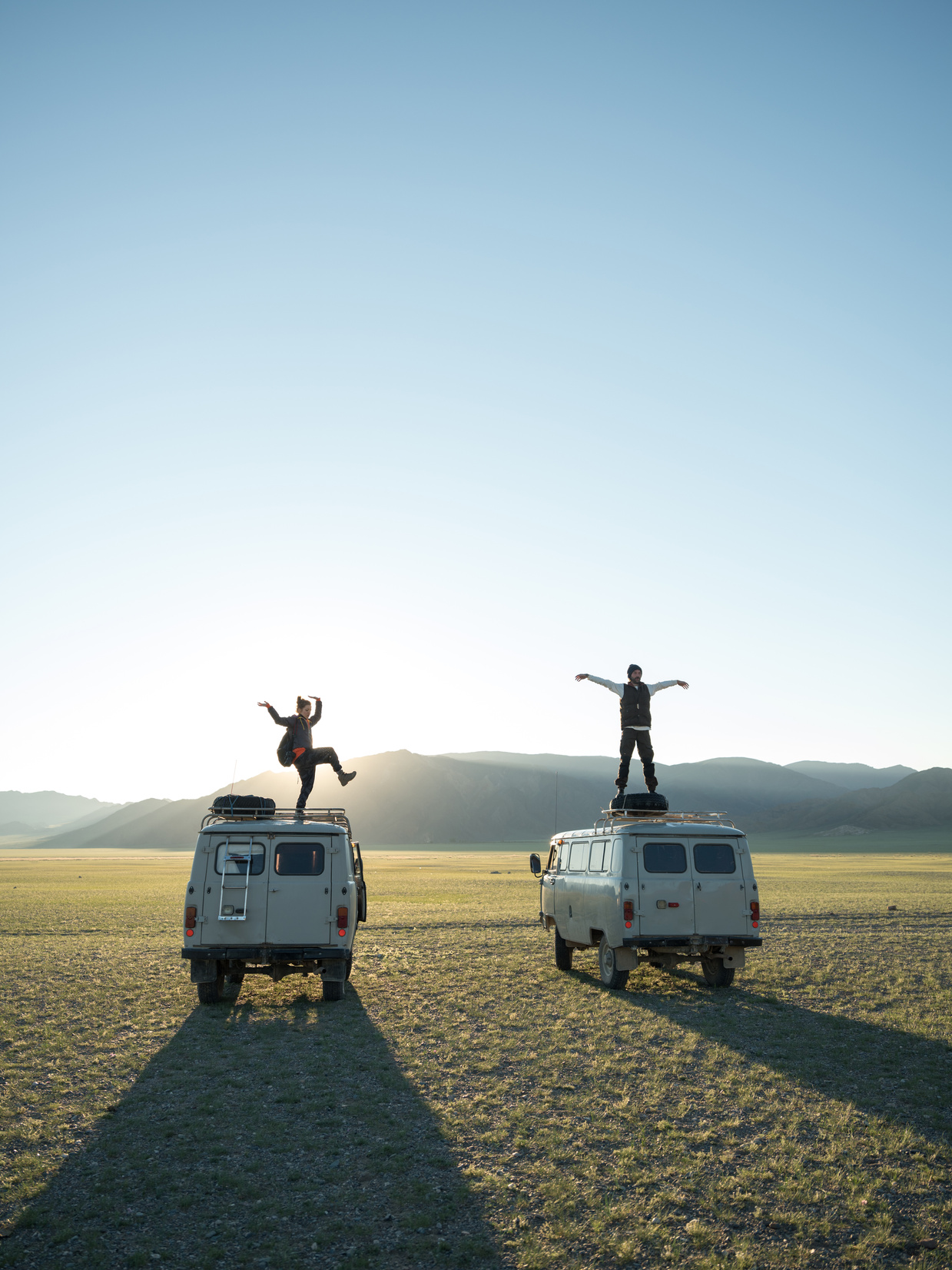 Travelers standing on vans in remote valley